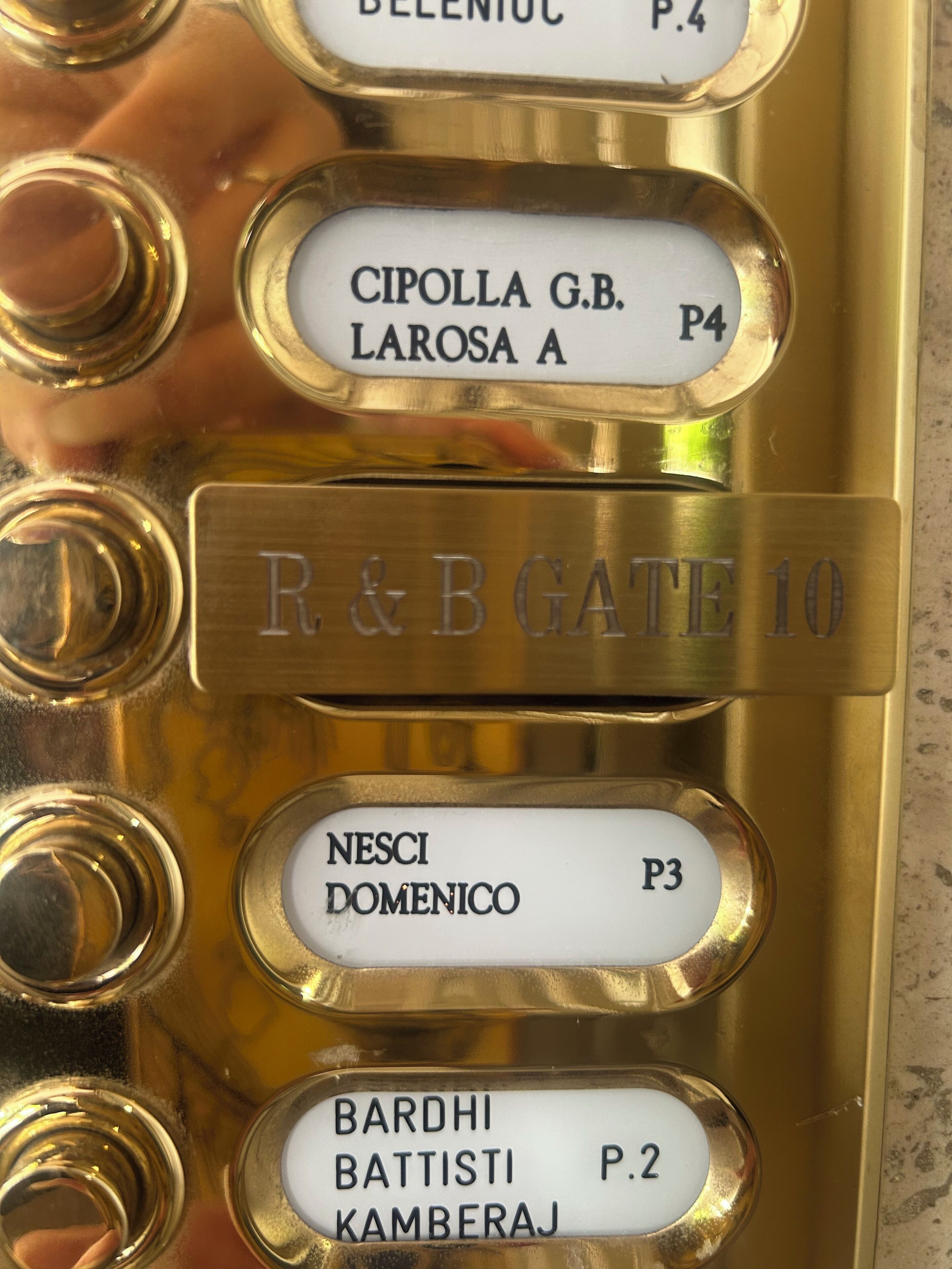 Gros plan d’une plaque en laiton portant les noms et les numéros des chambres d’un hôtel.