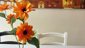 Ein Zimmer mit einer Wandmalerei eines historischen Gebäudes, einer Vase mit Blumen und einem weißen Stuhl.