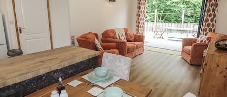 A dining area with a wooden table set for four, a sofa, and a view of the outdoors.