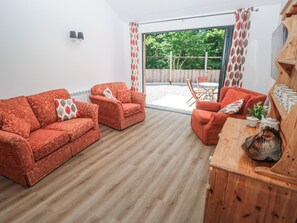 A furnished living room with a sofa set, a wooden sideboard, and a view through a glass door to an outdoor area. - Brookview Goldfinch (Haverfordwest)