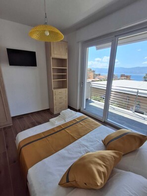 Un dormitorio con cama, armario, televisor y balcón con vistas.