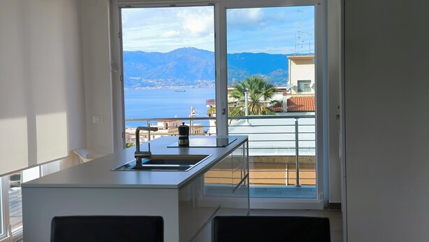 Une cuisine moderne avec vue sur la mer et les montagnes.