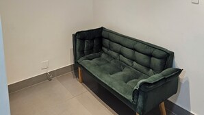 A room with a green sofa, a ceiling light fixture, and a power outlet on the wall. - Flat 109 Norte Novo e Completo 206 (Brasília)