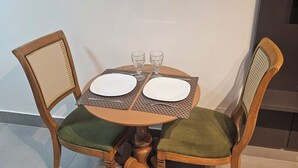 A round wooden dining table with two chairs, each with a cushioned seat and backrest. - Flat 109 Norte Novo e Completo 206 (Brasília)