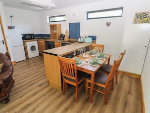 A compact kitchen with a dining area, a washing machine, and a microwave. - Brookview Kingfisher (Haverfordwest)