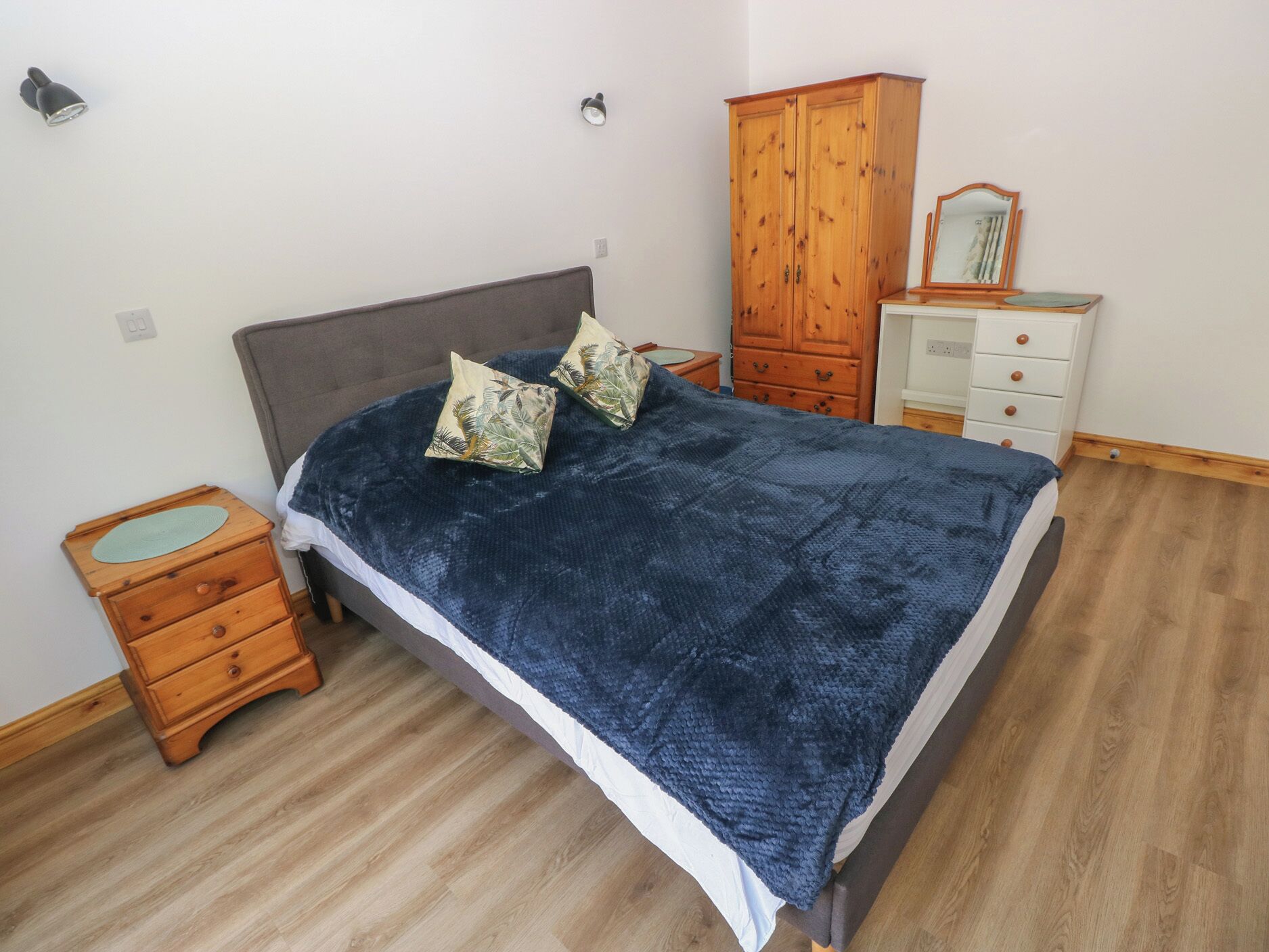 A bedroom with a bed, wooden nightstand, dresser, and wardrobe.