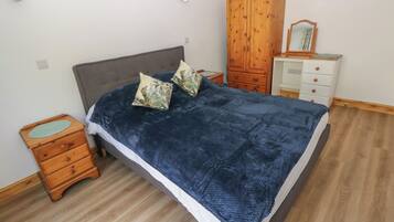 A bedroom with a bed, wooden nightstand, dresser, and wardrobe.