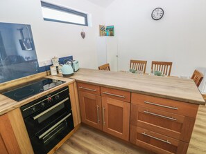 Una cocina con armarios de madera, una estufa negra y un ventanal sobre el fregadero.