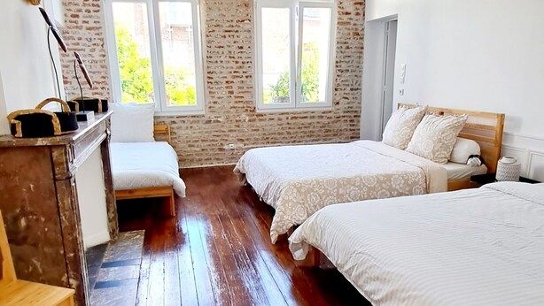 A room with two beds, a wooden bench, a brick wall, and a window. - Magnificent house in the heart of Douai (Douai)