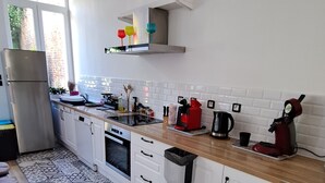 A modern kitchen with white cabinets, a patterned floor, and a window providing natural light. - Magnificent house in the heart of Douai (Douai)