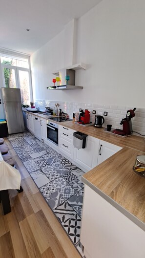 Een moderne keuken met witte kasten, een vloer met patroon en een raam voor natuurlijk licht.