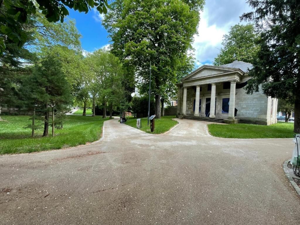 A building with a classical architectural style, a paved driveway, and a well-maintained lawn.