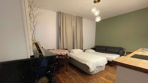 Een compacte kamer met een bed, een slaapbank, een kleine tafel en een marmeren openhaard.