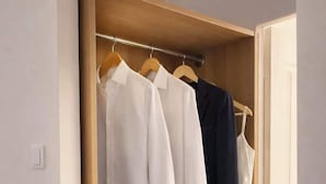 Een houten garderobe met kledingroede en lades.