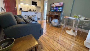 Uma sala de estar moderna com sofá, mesa de jantar com cadeiras, cozinha e TV na parede.