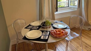 Mesa de jantar posta com pratos, talheres e um centro de mesa com uvas e frutas fatiadas.
