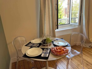 Ein Esstisch ist gedeckt mit Tellern, Besteck und einer Mittelstück-Anordnung aus Trauben und Obstscheiben.