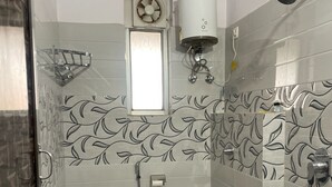A bathroom with a toilet, shower, and a window. - Spacious 9-bedroom hotel in charming Patna with AC comfort (Patna)