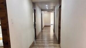 A long, narrow hallway with wooden flooring and white walls, leading to a bright room at the end. - Spacious 9-bedroom hotel in charming Patna with AC comfort (Patna)