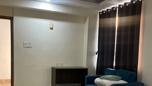 A hotel room with a bed, a sofa, a small table, and a TV stand. - Spacious 9-bedroom hotel in charming Patna with AC comfort (Patna)