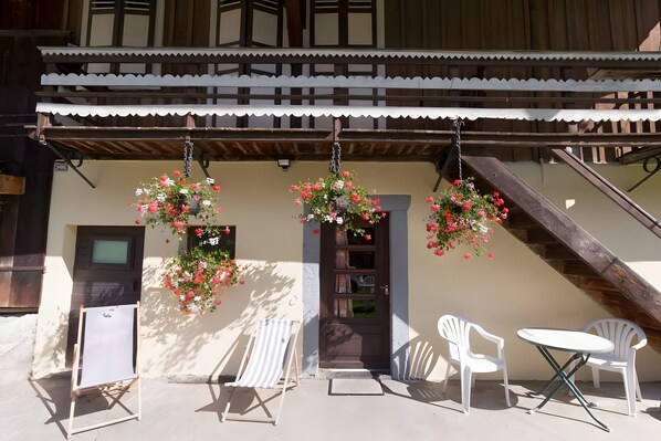 A building with a traditional architectural style, a balcony with hanging flower baskets, and outdoor seating.