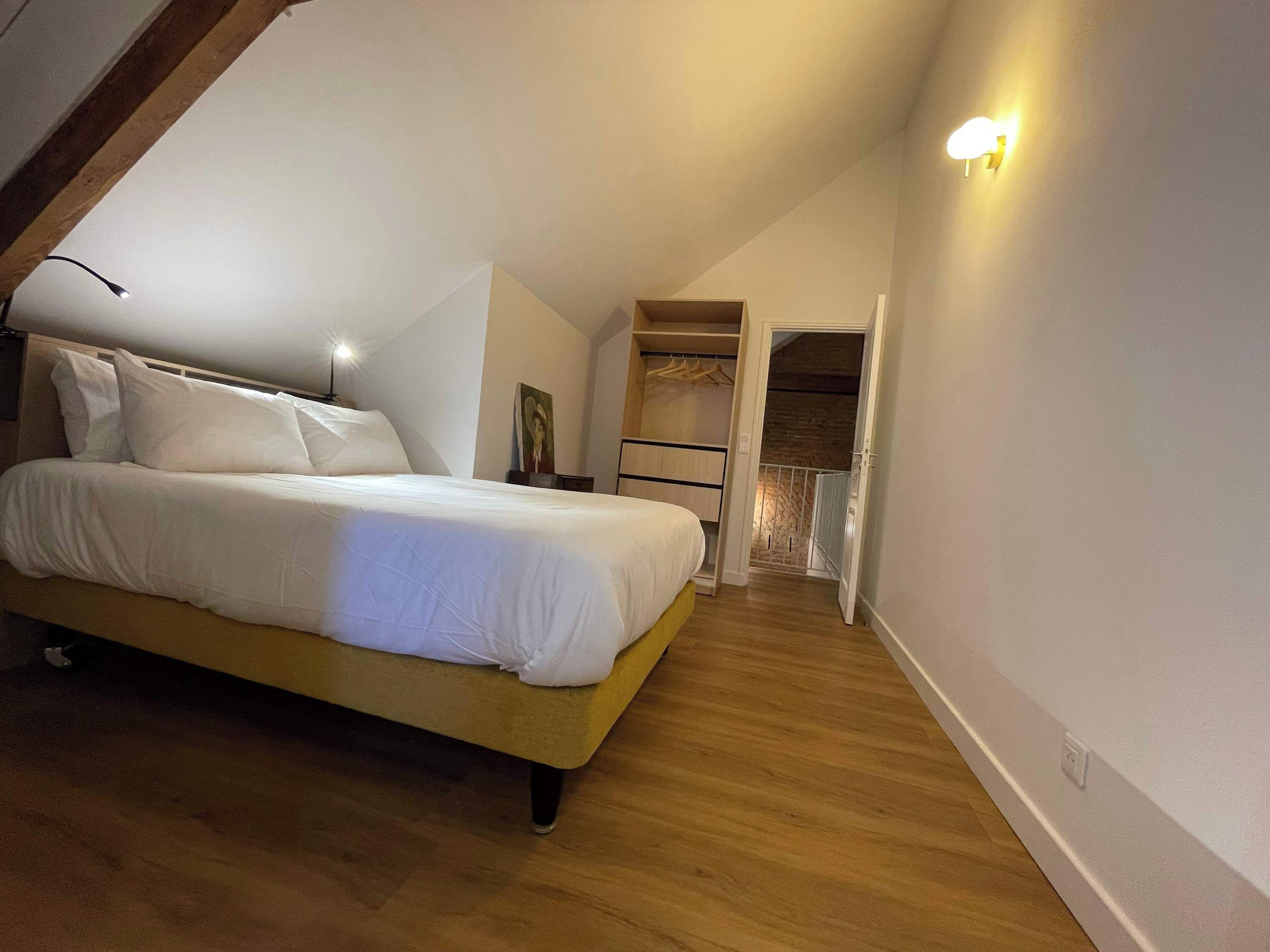 A bedroom with a bed, a nightstand, a wardrobe, and a door leading to a balcony.