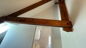 A wooden beam structure in a room with white walls and a visible door in the background. - Spacious Duplex • 2 Suites • Space & Privacy • Fully Equipped • Amiens Centre • 5-min Walk to Station • Parking on Site (Amiens)