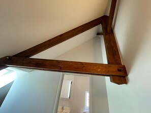 Ein Raum mit weißen Wänden und einem sichtbaren Türansatz, dessen Dach aus Holzbalken besteht.
