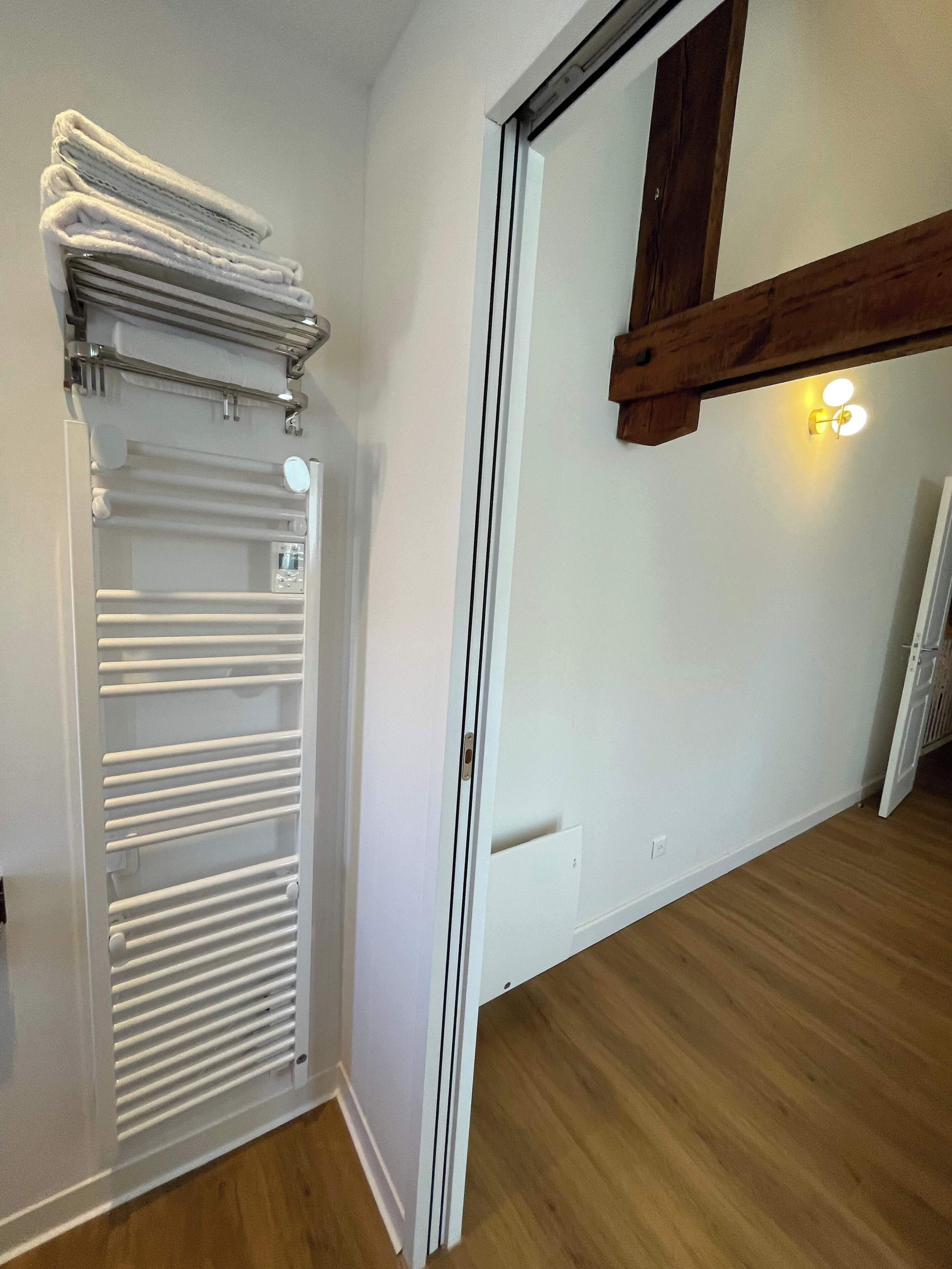 A room with a white radiator, wooden flooring, and a partially open door leading to another room.