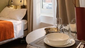 A hotel room with a bed, a table set for dining, a window with curtains, and a vase with a branch decoration. - Spacious Quiet Studio • Fully Equipped • Amiens Centre • 5-min Walk to Station • Parking on Site (Amiens)