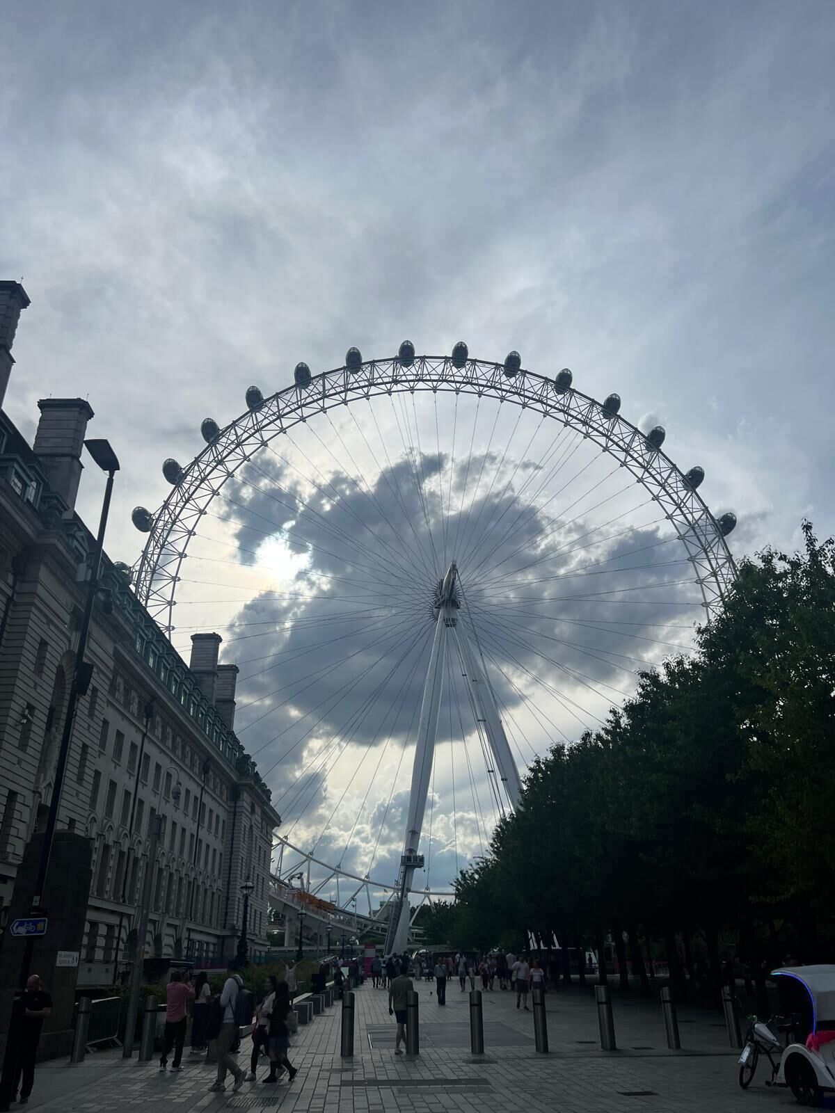 A large Ferris wheel with a classic design, surrounded by a paved walkway and historic buildings.