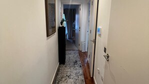 Un pasillo estrecho con alfombra estampada, suelo de madera y paredes blancas.