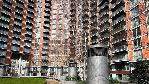 Un edificio moderno con fachada curva, varios balcones y una estructura cilíndrica central.