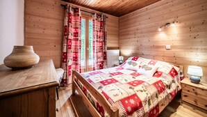 Una stanza in una baita di legno con un letto, un comodino, una lampada e un vaso su un tavolo.