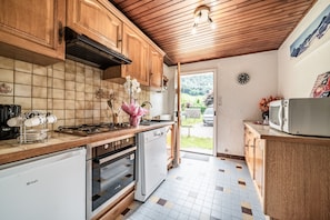 A kitchen with wooden cabinets, a tiled backsplash, a gas stove, a dishwasher, and a microwave.