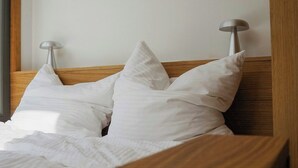 A neatly made bed with white linens and pillows, a wooden headboard, and two bedside lamps. - Modern tiny house with private lake access (Walsrode)