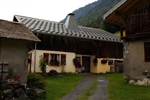 Un bĂątiment rustique avec un toit en pente, une porte en bois et un petit porche.