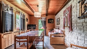 Ein Holzblockhaus-Innenraum mit Esstisch, Stühlen, einer Couch und einem Fernseher.