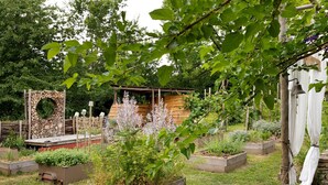A garden with raised beds, a wooden structure, and a bell.