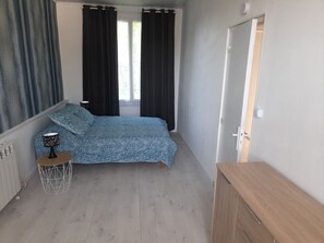 Une chambre à coucher avec un lit, une table de chevet, une lampe, un radiateur et une porte.