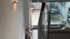 Et moderne interiør med en trappe, der fører op til en balkon, et spiseområde og udsigt til gaden.