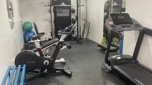 Et fitnesscenter med løbebånd, styrkeudstyr og træningsbolde.