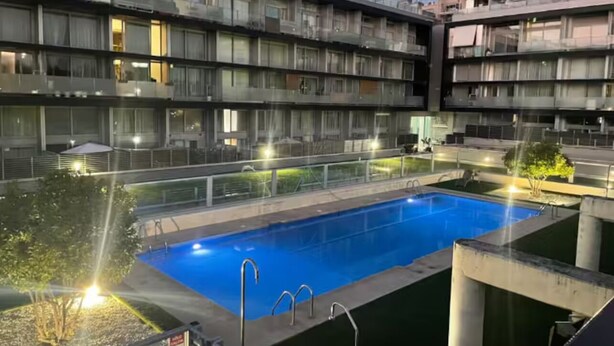 En pool med udsigt til en høj bygning med altaner og vinduer.
