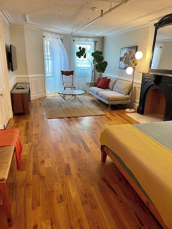 A living room with a sofa, a coffee table, a chair, a floor lamp, and a fireplace.. Brooklyn Garden Apartment