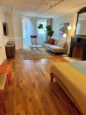 Ein Wohnzimmer mit einer Couch, einem Couchtisch, einem Sessel, einer Stehlampe und einem Kamin.