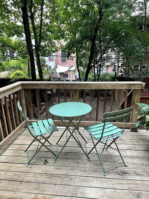 Eine Holzterrasse mit einem runden Tisch und zwei Stühlen.