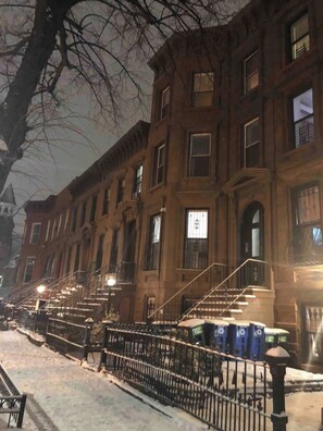 Fileira de edifícios de tijolo com várias janelas e uma rua coberta de neve.