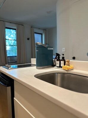 Eine Küche mit einem modernen Wasserhahn, einer Kaffeemaschine und Pflegeprodukten auf der Arbeitsfläche.