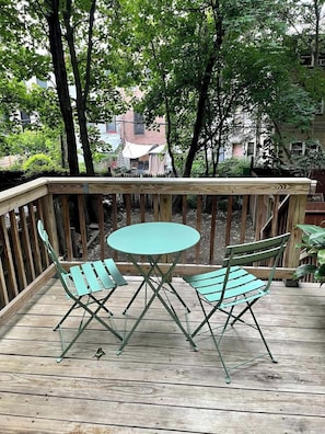 Eine Holzterrasse mit einem runden Tisch und zwei Stühlen.