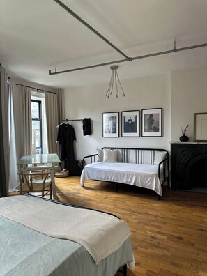 A bedroom with a bed, a small table, a chair, a radiator, and a fireplace. - Brooklyn artistic studio apartment! (Brooklyn)